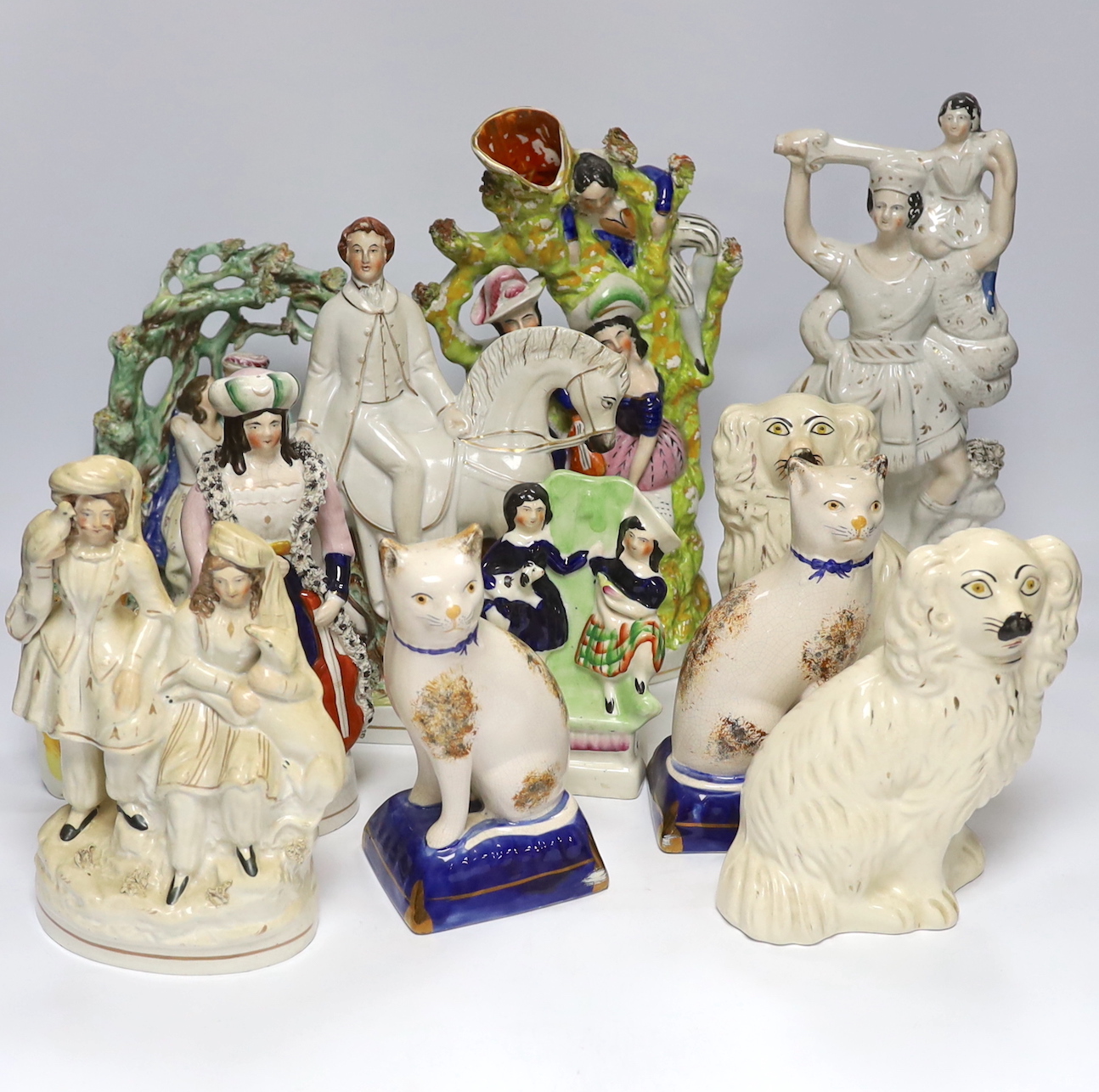 Seven Staffordshire flat backs, including a gentleman on horse back, two seated lovers, a similar pair of King Charles Spaniels, and a pair of Staffordshire style cats, tallest 32cm